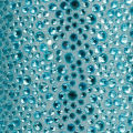 A tube of clear adhesive beside a clear pouch filled with silver and iridescent rhinestones of various sizes and shapes.