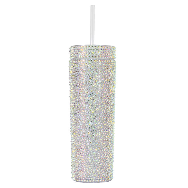 A tall silver tumbler covered in rhinestones with a clear straw and a smooth shiny surface.
