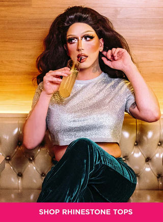 Model wearing a silver rhinestone crop top with green velvet pants while holding a drink